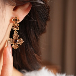 Close-up of vintage golden flower earrings with amber crystals on a model