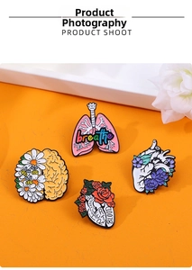Artistic anatomy enamel pins set featuring floral brain and heart designs on orange background