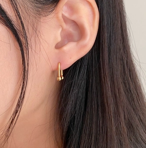 Close-up of gold geometric U-link chain earrings with beads worn by a model