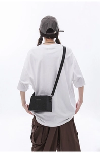 Rear view of model wearing a black rectangular crossbody box bag with white casual t-shirt