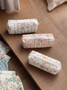 Detailed close-up of quilted floral pencil cases in blue, orange and beige cotton fabric