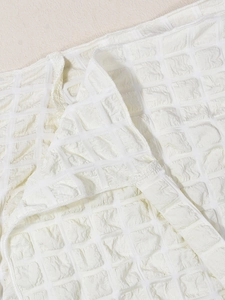 Macro shot of cream high waist skirt fabric with seersucker texture and neat stitching