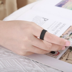 Close-up of matte black woven mesh ring worn by model over lifestyle magazine
