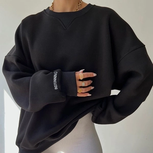 Detail of knitted sweatshirt cuff with white letter print and ribbed neckline texture