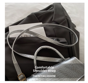 Detail view of silver crocodile embossed texture and adjustable shoulder strap on small handbag
