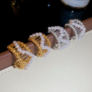 Close-up of hollow 18k gold plated pearl earrings with detailed metal wire weaving