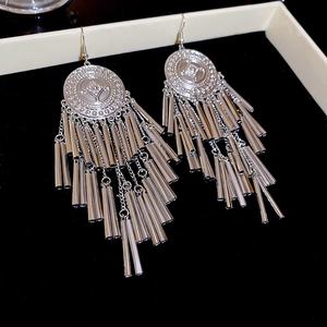 Detail view of silver vintage round earrings with long metal tassel fringe on black surface