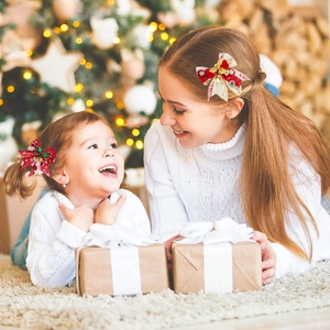 Red and cream Christmas bow hair clips with bells on a festive tree background