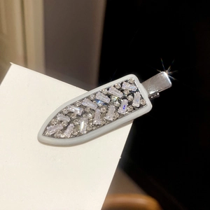 Close-up of silver dagger-shaped hair clip with sparkling white zircons and metal finish