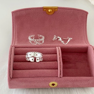 Trois bagues en argent avec cœurs évidés et nœuds sur fond de velours rose