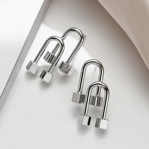 Minimalist silver geometric U-shaped stud earrings with cubic design on white surface