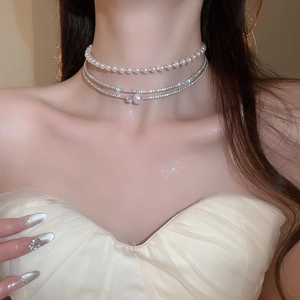 Close-up of layered pearl choker necklace with sparkling rhinestones on female neck