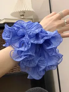 Close-up of royal blue pleated organza scrunchie worn on wrist for size reference