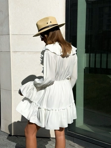Detail of white V-neck chiffon dress showing ruffled lantern sleeves and tiered hemline