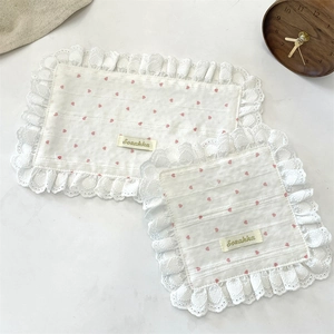 Detail of white quilted place mat with pink hearts and delicate lace borders