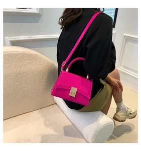 Detail of fuchsia crocodile pattern leather bag with gold twist lock and woven handle