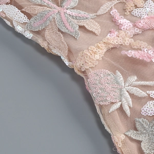 Detail view of pink mesh fabric with sequins and silver floral embroidery on a party dress