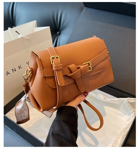 Detail of caramel lychee leather crossbody bag with knot strap and heart print silk scarf