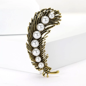 Detail view of golden alloy feather brooch featuring elegant gradient white imitation pearls