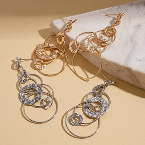 Textured geometric multilayer gold and silver hoop earrings on marble display