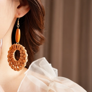Détail de boucles d'oreilles bohèmes en rotin avec perle en bois sur une mannequin