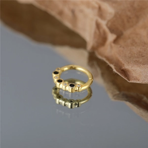 Close-up of golden S925 silver hoop ring with alternating black and white zircons
