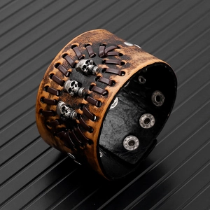 Macro detail of brown leather punk bracelet featuring skull studs and woven cords