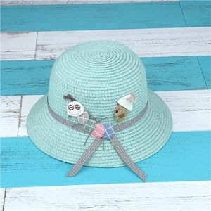 Detail of mint green straw hat featuring caterpillar and mushroom fabric patches