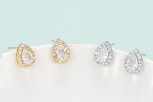Macro shot of halo pear-shaped zircon stud earrings in gold and silver finishes