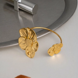 Dettaglio del bracciale rigido a fiori dorati con petali testurizzati e finitura oro 18K