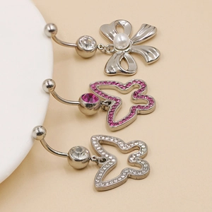 Detailed macro view of silver stainless steel belly rings with pearls and crystal bows