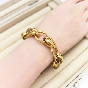 Close-up of chunky gold geometric link bracelet with twisted rope and oval pig nose texture