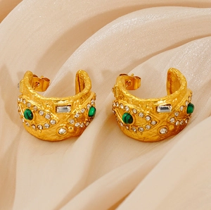 Gros plan de boucles d'oreilles dorées martelées avec pierre de malachite et cristaux