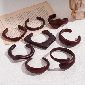 9-piece set of vintage brown acrylic chunky geometric open bangles on a textured background