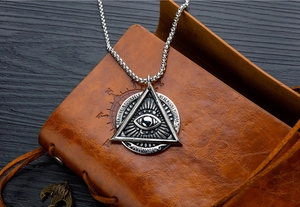 Détail macro du pendentif œil de la providence gothique sur un livre en cuir vintage
