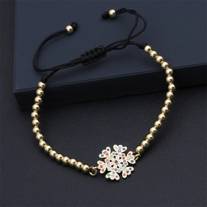 Detail eines verstellbaren Armbands mit goldenem Schneeflocken-Anhänger und bunten Zirkon