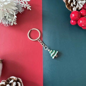 Christmas tree keychain with green white ornaments on festive red and green background