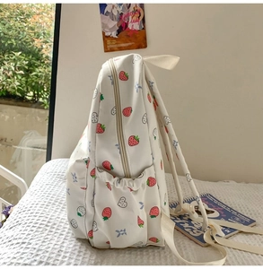 Detail of cute strawberry print canvas backpack with side pocket for students