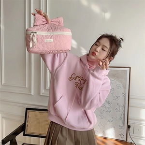 Détail d'une trousse à maquillage rose matelassée avec poignée nœud et fermeture éclair