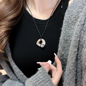 Close-up of liquid metal style silver heart pendant on a black cord necklace