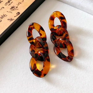 Detailed macro view of acrylic tortoise shell chain link earrings on a white surface