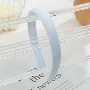 Soft plush light blue headband for women displayed on a transparent display stand