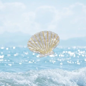 Detailed close-up of shell shaped acetate hair claw with golden lines on beach background