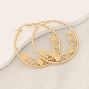 Gold stainless steel hoop earrings with internal heart pattern on white marble platform