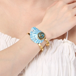 Detail of gold-plated ocean shell bracelet with blue enamel and white pearl accents