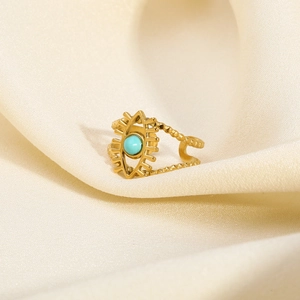 Detail of gold-plated evil eye ring with blue stone on cream silk background