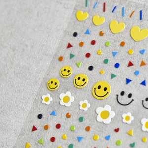 Vue macro de stickers 3D gaufrés pour ongles avec smileys colorés et marguerites