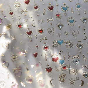 Macro view of 3D embossed nail stickers featuring gold-trimmed hearts and celestial motifs