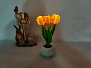 Cozy LED tulip night light in a ceramic pot emitting a warm orange glow on a bedside table