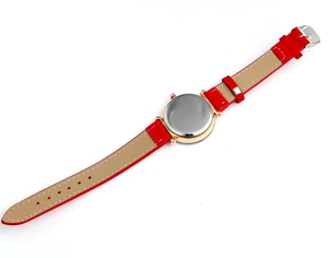 Detail of red leather watch strap with white stitching and rose gold casing back